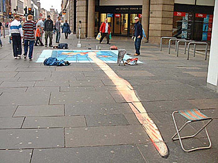 A pavement drawing of an elongated foot and leg leading to a red and blue object in the distance