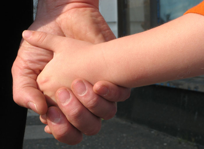 Photo of a Father holding his son's hand.