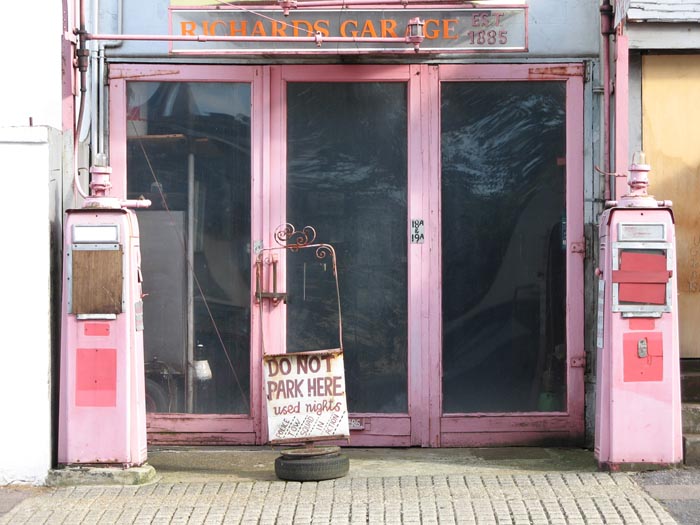 A photo of a garage with old boarded up petrol/gas pumps