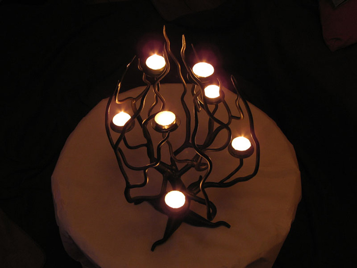 Photo of a 7 branched candelabra in the shape of a tree, with candles light.